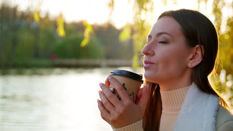 woman enjoying coffee in the park at sunset