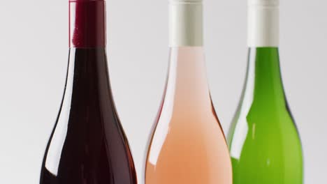 three diverse types of wines in bottles over white surface