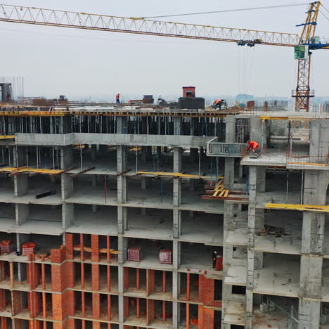 Massive residential building at construction site. Drone aerial view of new development with cityscape. Wide view of a new building with urban city behind.