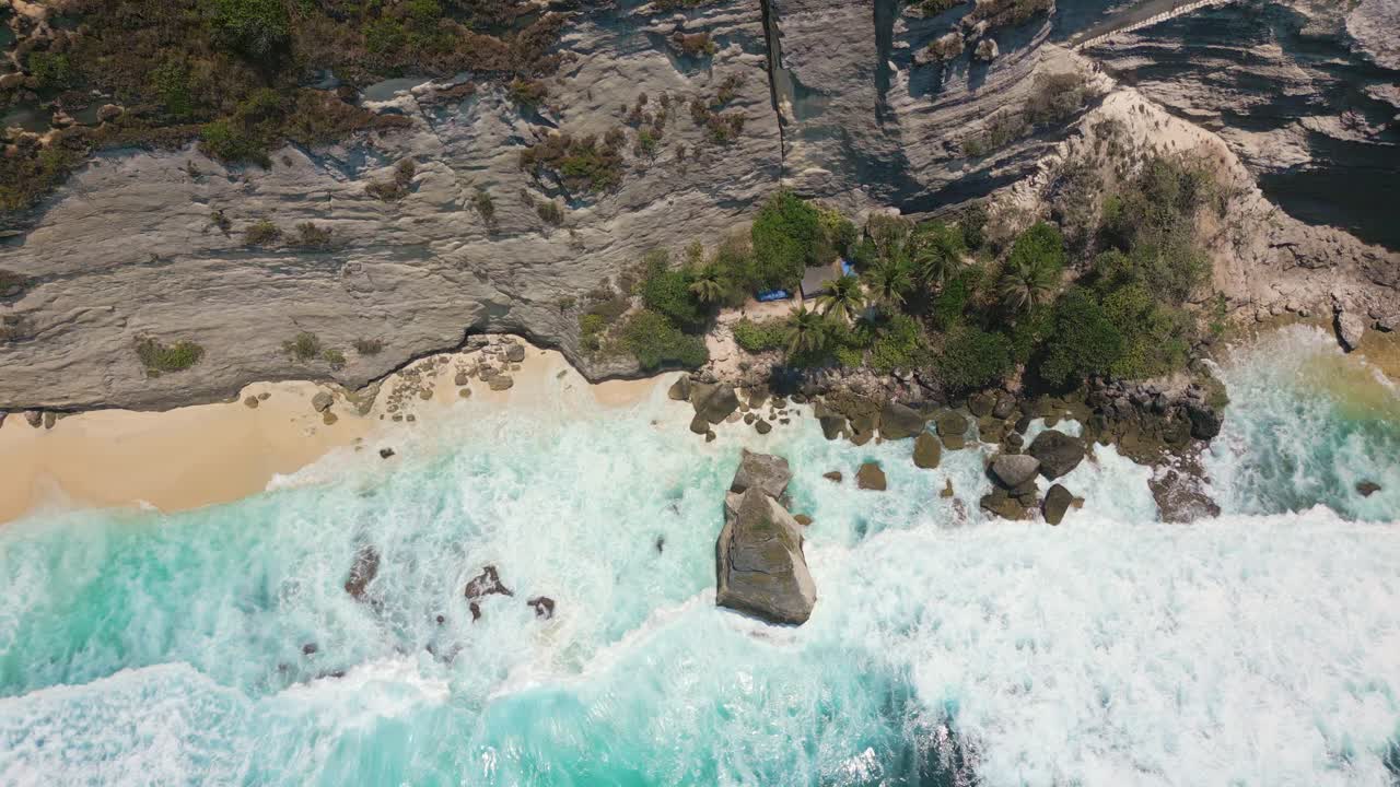 Top down drone view of a sandy beach battered by ocean waves (Diamond Beach, Nusa Penida)