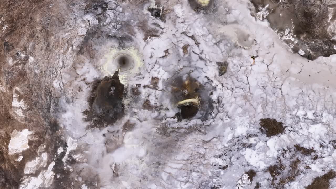 Splashing hot spring field in Iceland. Aerial top down. Boiling water of volcano. Descend shot