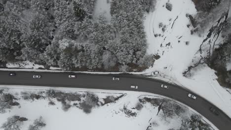 a busy highway cutting through a snow-covered landscape, with vehicles traveling amidst a serene winter setting