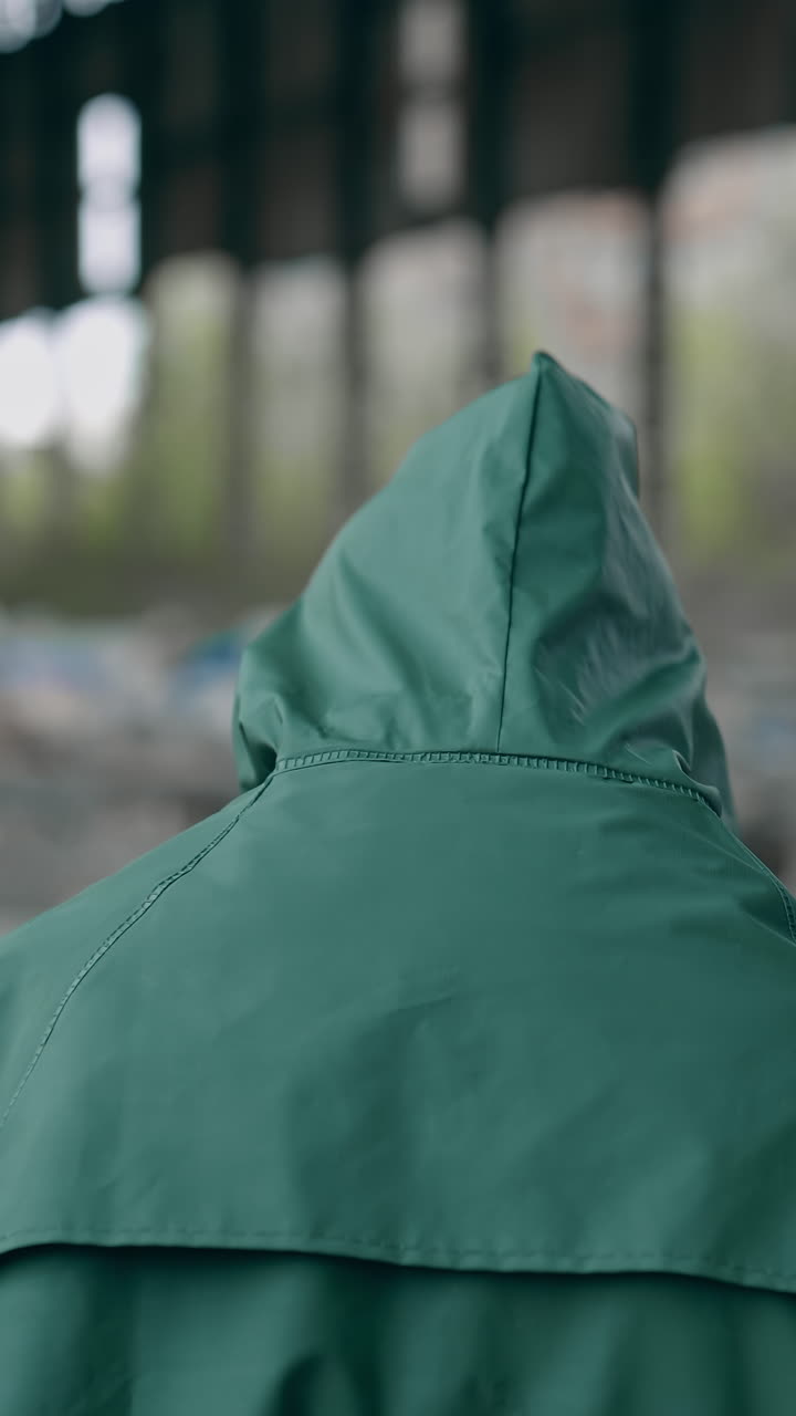 Human in radioactive territory. Person in a hazmat suit and gas mask walking in empty ruined building. Abandoned place after chemical attack. Rear view. Vertical video