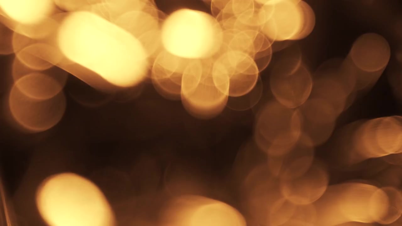 Particelle Bokeh Astratte di Luce Dorata Fluttuanti su Sfondo Nero