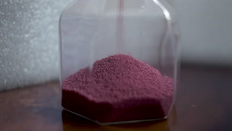 red sand piles up in a sand timer