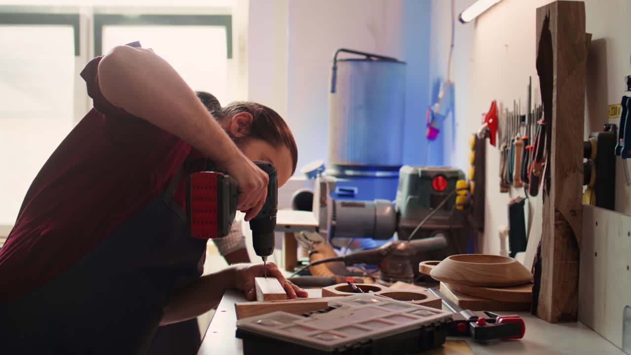 Cabinetmaker drills hole into lumber block, doing furniture assembling
