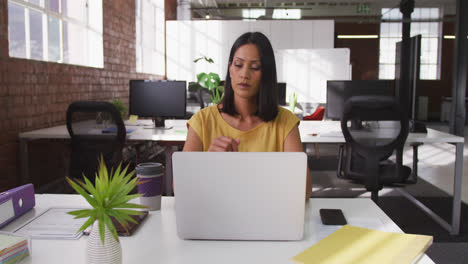 Empresaria-De-Raza-Mixta-Sentada-En-Un-Escritorio-Usando-Una-Computadora-Portátil-Mirando-Hacia-El-Futuro