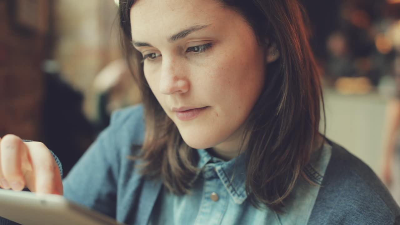 mujer usando una pantalla táctil de una tableta en un café