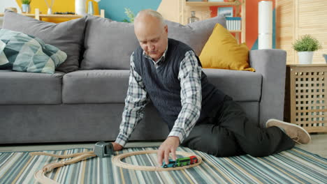 Senior Man Playing with Wooden Train Set