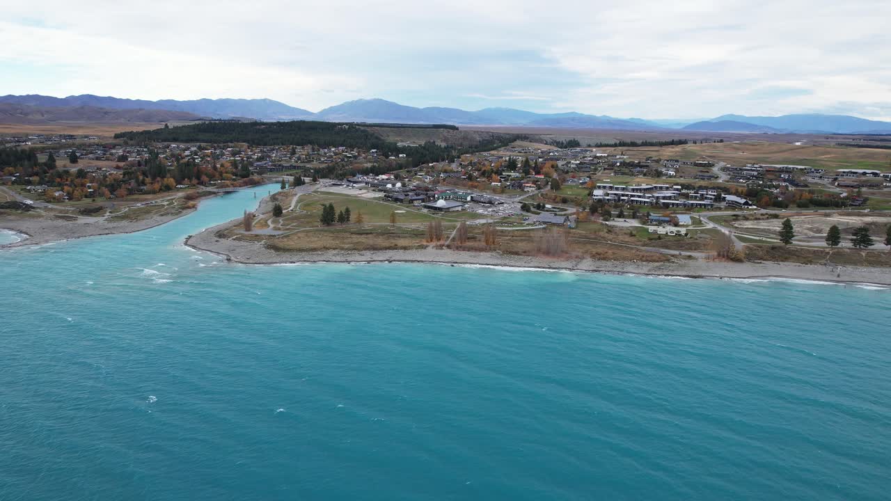 Tekapo River Outlet Flowing Into Lake Tekapo With Township On Shore. Canterbury, New Zealand. wide aerial shot