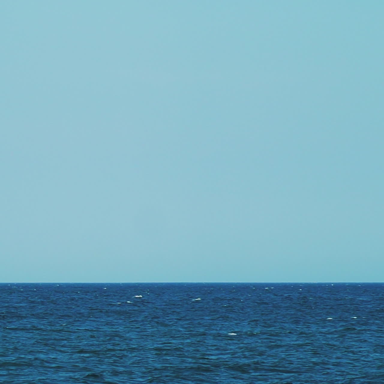 A sailboat, yacht on the horizon in the sea. Horizon of the sea. Blue water and sky