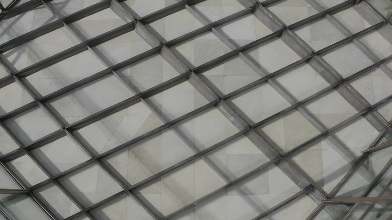 Panoramica della telecamera che mostra un filo piegato su una griglia metallica che si muove all'interno, proiettando ombre su un pannello chiaro.
