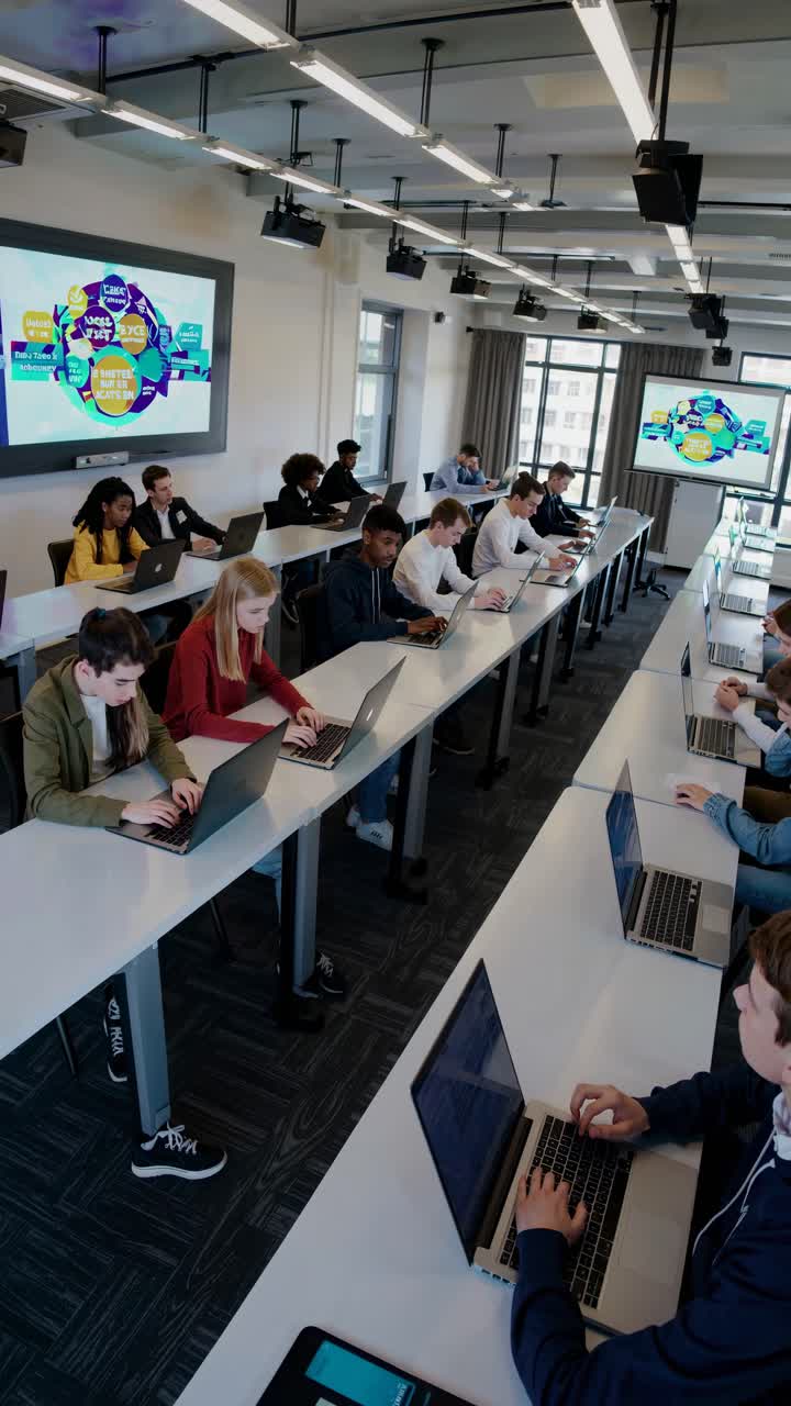 Students in a classroom using laptops. Diverse group, mixed genders, focused on screens. Modern