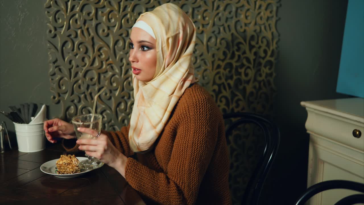 Woman in hijab enjoying dessert and drink in a cafe