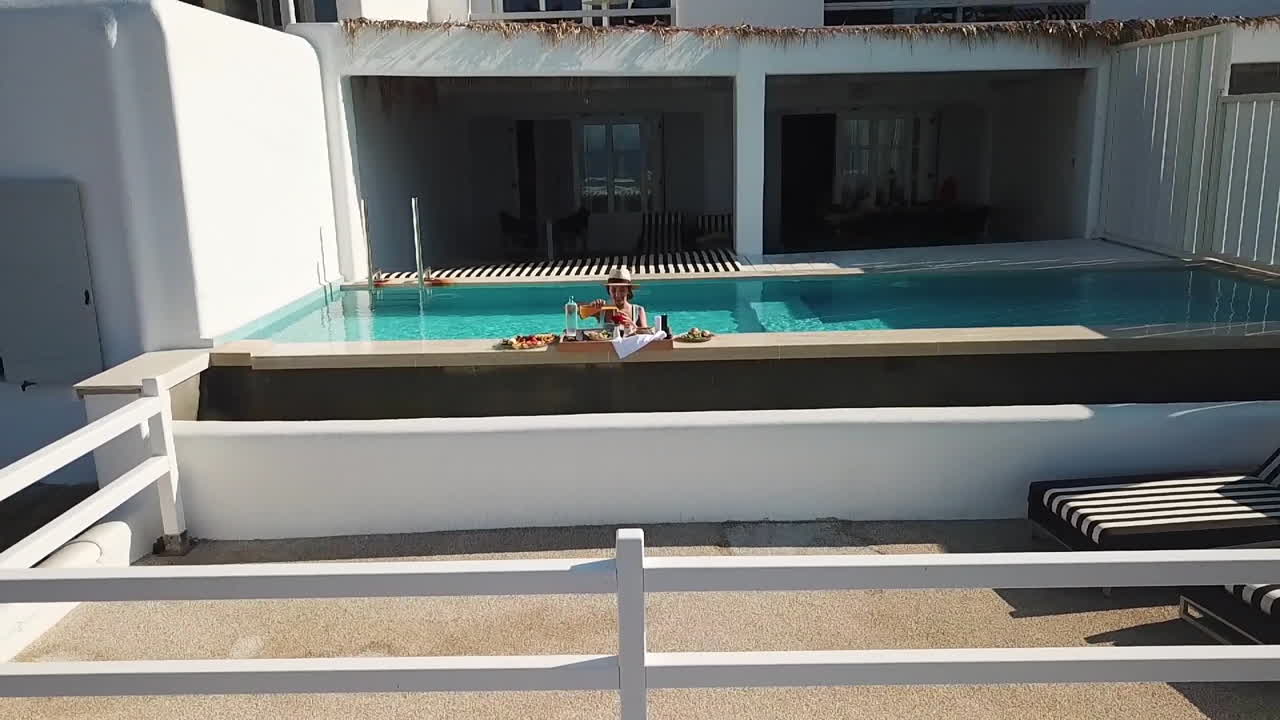 счастливая женщина в частном бассейне на роскошной летней вилле и завтрак, подаваемый на берегу бассейна, откидная антенна