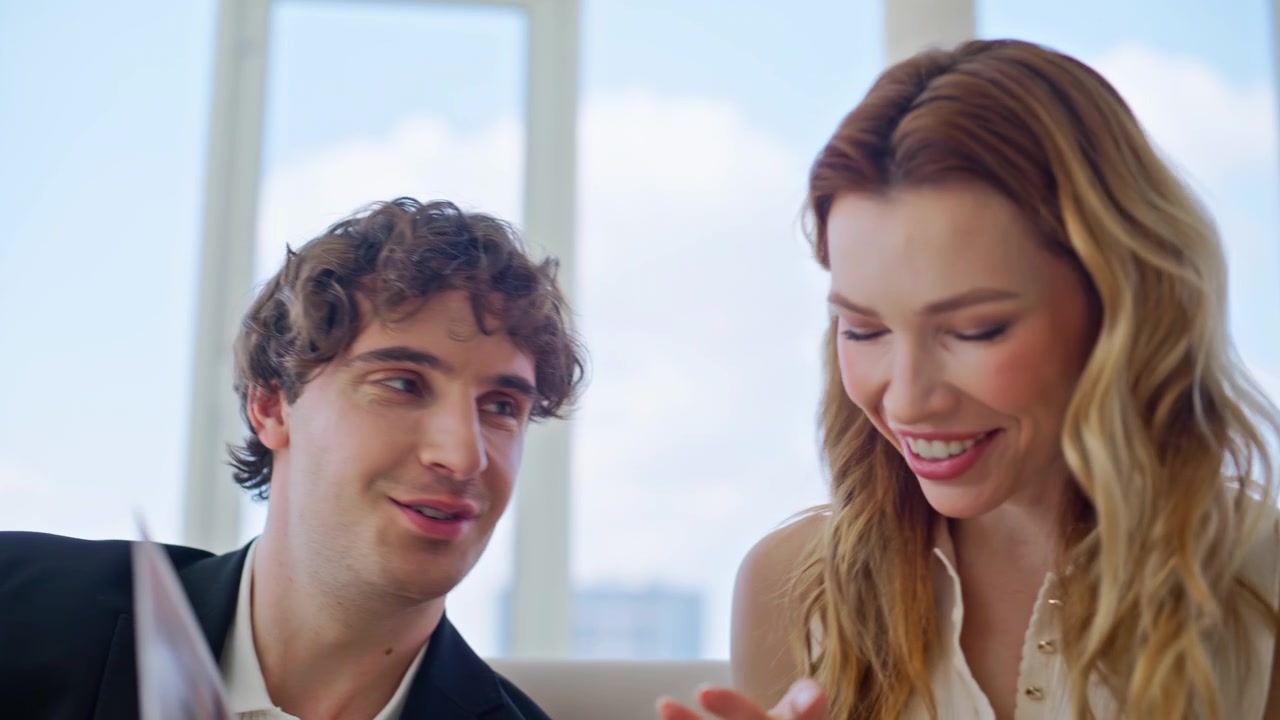 Muž ukazuje fotoalbum usmívající se přítelkyni doma. Detail páru prohlížejícího knihu
