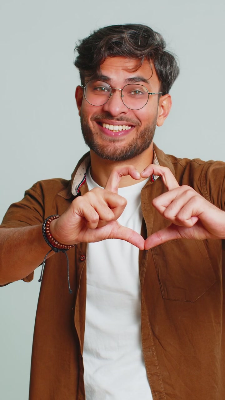 Un hombre guapo sonriente hace un gesto de corazón demuestra un signo de amor expresa buenos sentimientos y simpatía