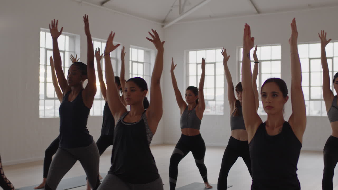 grupo de clase de yoga de mujeres multirraciales practicando pose guerrera disfrutando de un estilo de vida saludable haciendo ejercicio en el gimnasio al amanecer