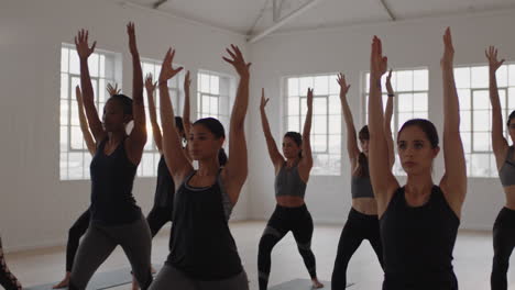 Yoga-Kursgruppe-Gemischtrassiger-Frauen,-Die-Kriegerpose-Praktizieren-Und-Einen-Gesunden-Lebensstil-Genießen-Und-Bei-Sonnenaufgang-Im-Fitnessstudio-Trainieren