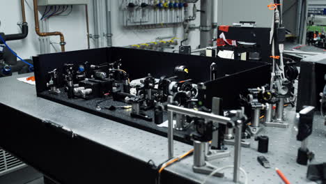 panorámica horizontal sobre una mesa óptica con diferentes elementos láser y espejo para mediciones científicas precisas