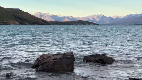 two rocks at the shore of lake tekapo on tranquil evening