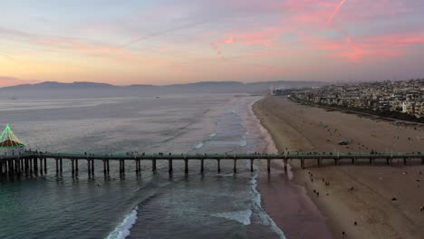 gente caminando en el muelle de la playa de manhattan y en la playa al atardecer en california, estados unidos