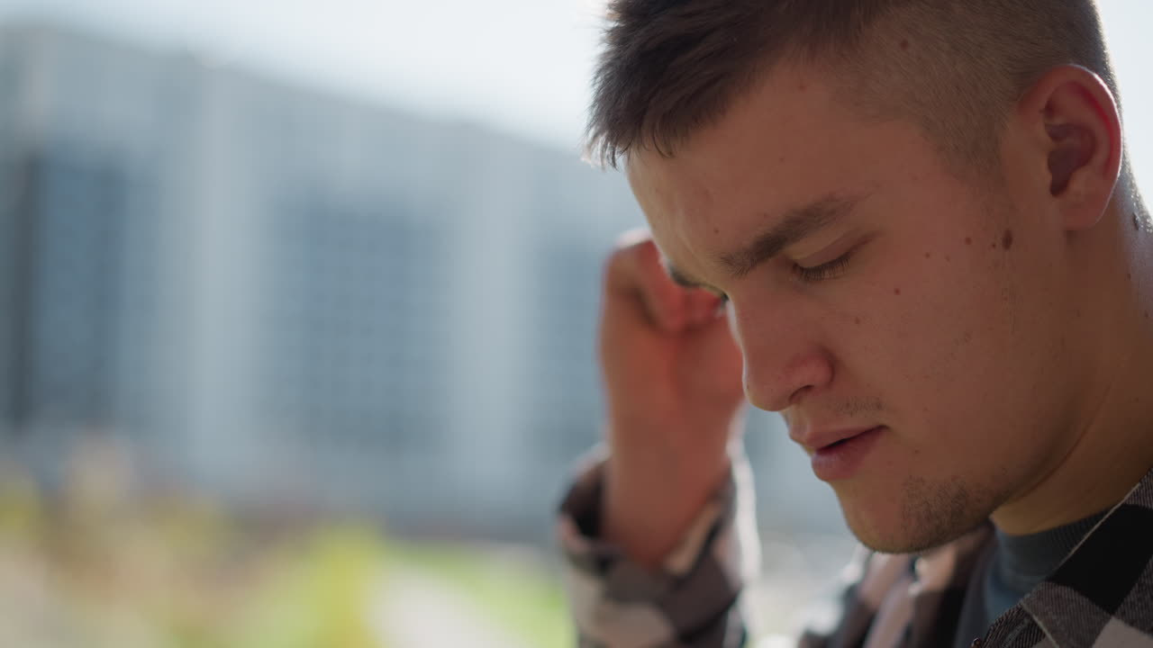 close up of man retrieving cigarette from ear raising lighter to tip sparks ember prepares inhale smoke against softly blurred urban background under natural daylight with sunlit face glow