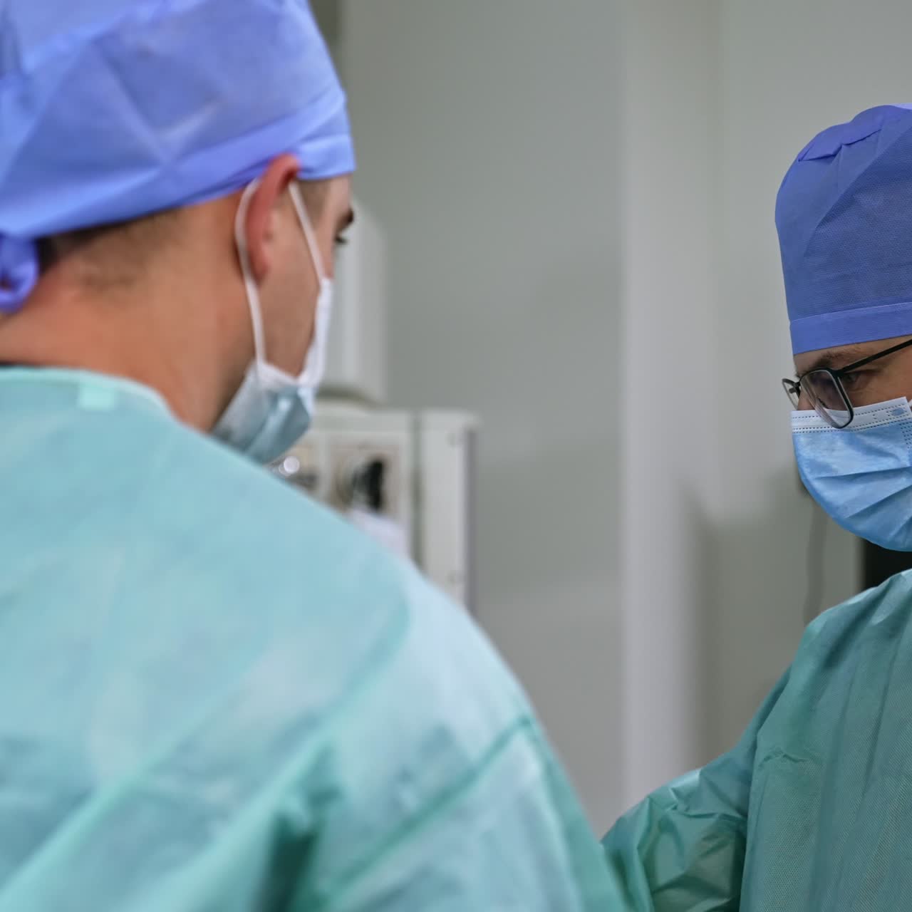 Calm confident male doctors working at surgery room. Medics focused on work in modern hospital. Blurred backdrop