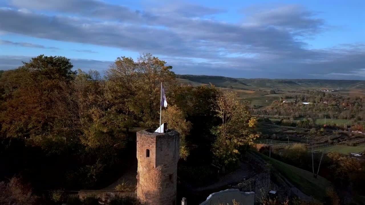 Fast orbiting shot of the medieval castle ruin 'Weibertreu' on a hill near the village ‚Weinsberg‘ in warm autum colors on a sunny day