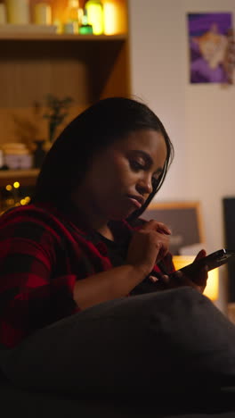 woman using phone at night on couch