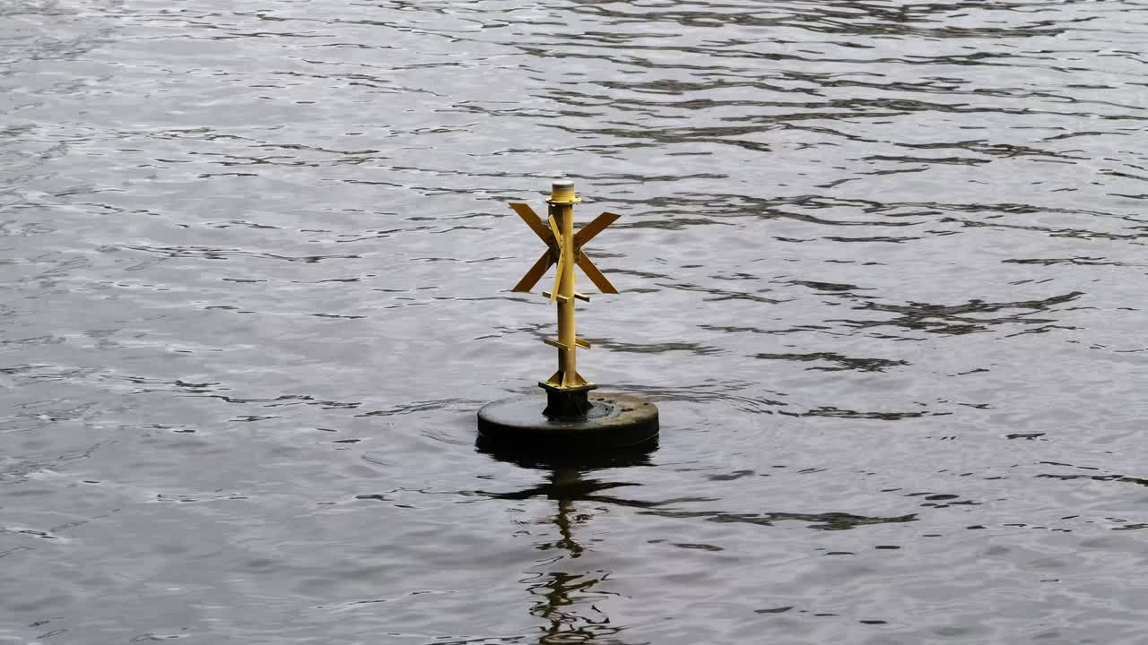 Yellow buoy floating and bobbing on the Thames in London.