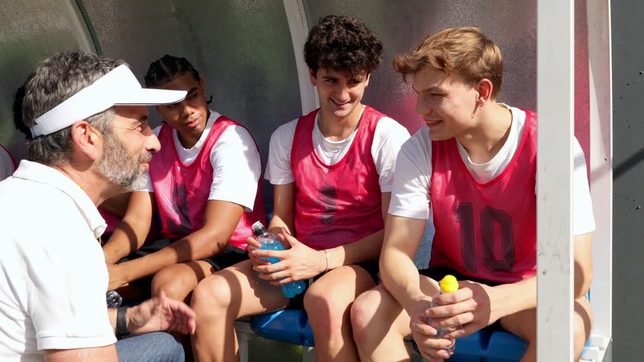 Soccer team with their coach discussing strategy on the bench