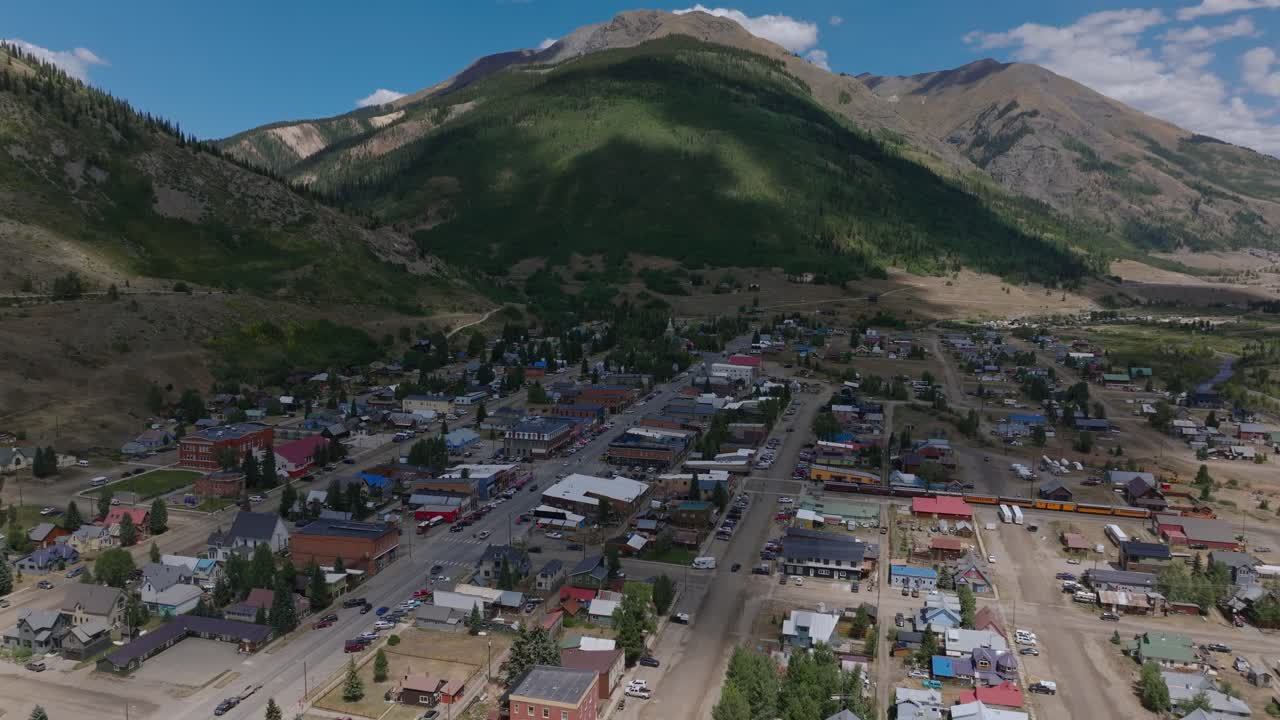 La città di Silverton si estende in una valle di alta quota sotto una luminosa luce estiva, riprese aeree orbitali mentre un'ombra di nuvola la attraversa, Colorado, USA.