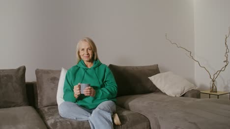 senior woman relaxing on couch with coffee/tea