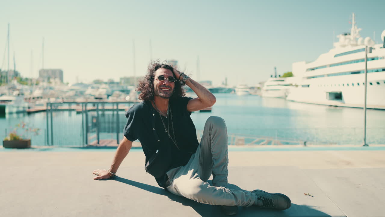 Man sitting by the harbor with yachts in the background