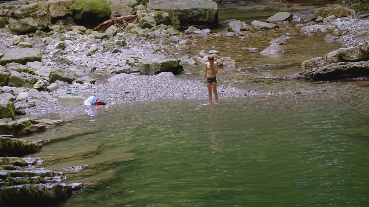 Garçon jouant dans un ruisseau de montagne
