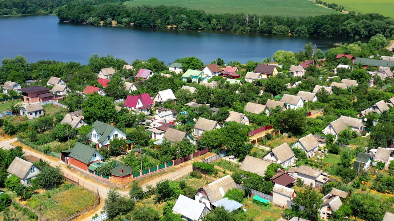 Countryside near the river. Flight over the roofs of village buildings on the background of picturesque nature. Amazing nature in rural place. Aerial view.