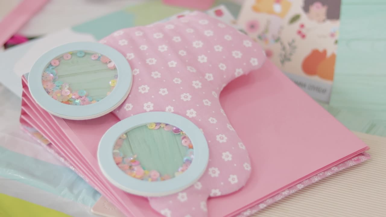 ピンクのスクラップブック・アルバムで花のパターンが付いており手作りのテーブルにセッキン・サッカーが置かれています