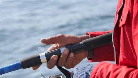 close-up of a fisherman's hand holding a fishing rod and reel