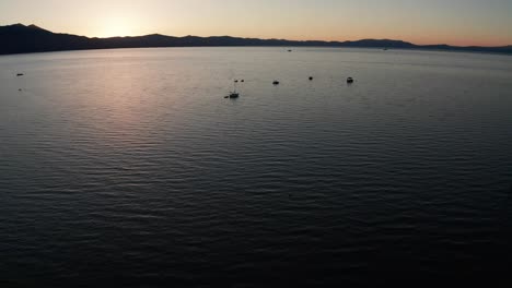 Low-tilting-up-aerial-shot-of-boats-on-Lake-Tahoe-at-sunset