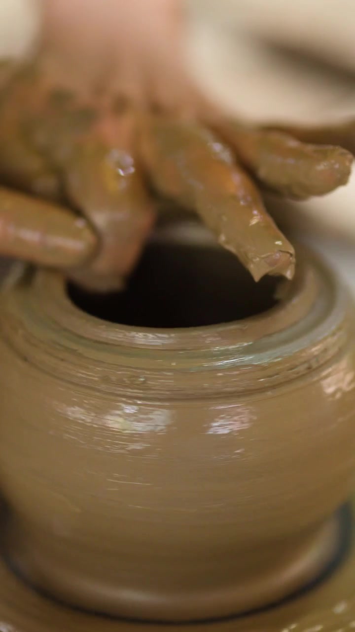 Primo piano delle mani di un vasaio che modellano un vaso di ceramica su un tornio rotante a Nonthaburi, Thailandia.
