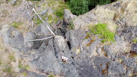 aerial - birdseye view of woman meditating on rocky cliff surrounded by trees