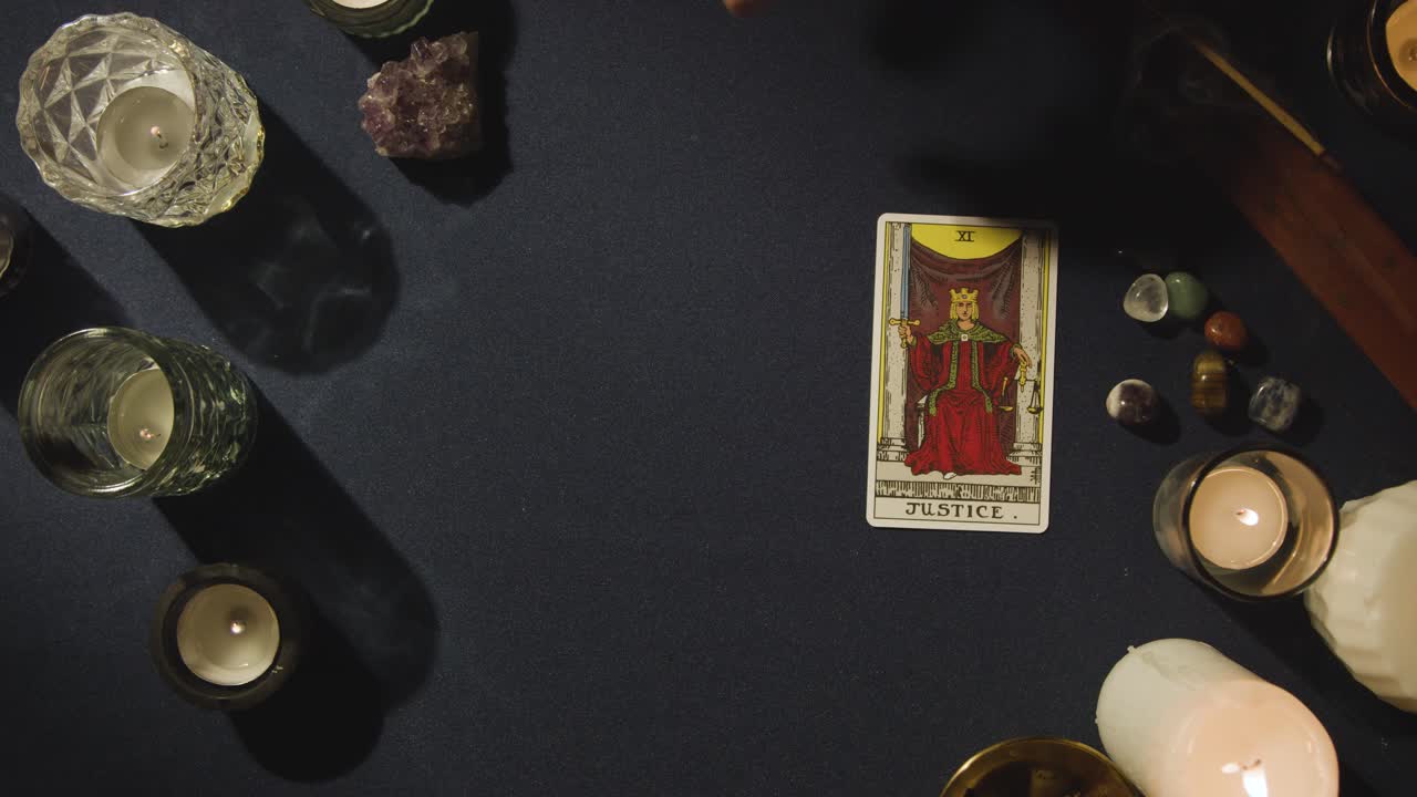 disparo desde arriba de una persona que da lectura de cartas de tarot colocando la tarjeta de justicia en la mesa