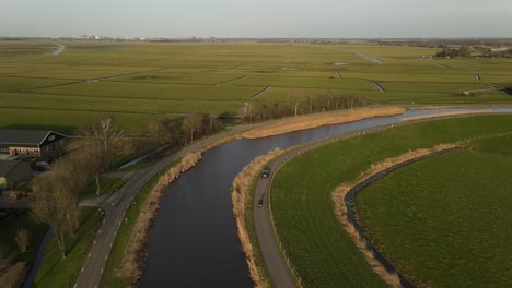 Car-and-motorcycle-riding-together-along-Waverdijk-road-in-green-rural-land