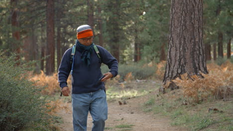 asian man using his smartphone in a forest, front view