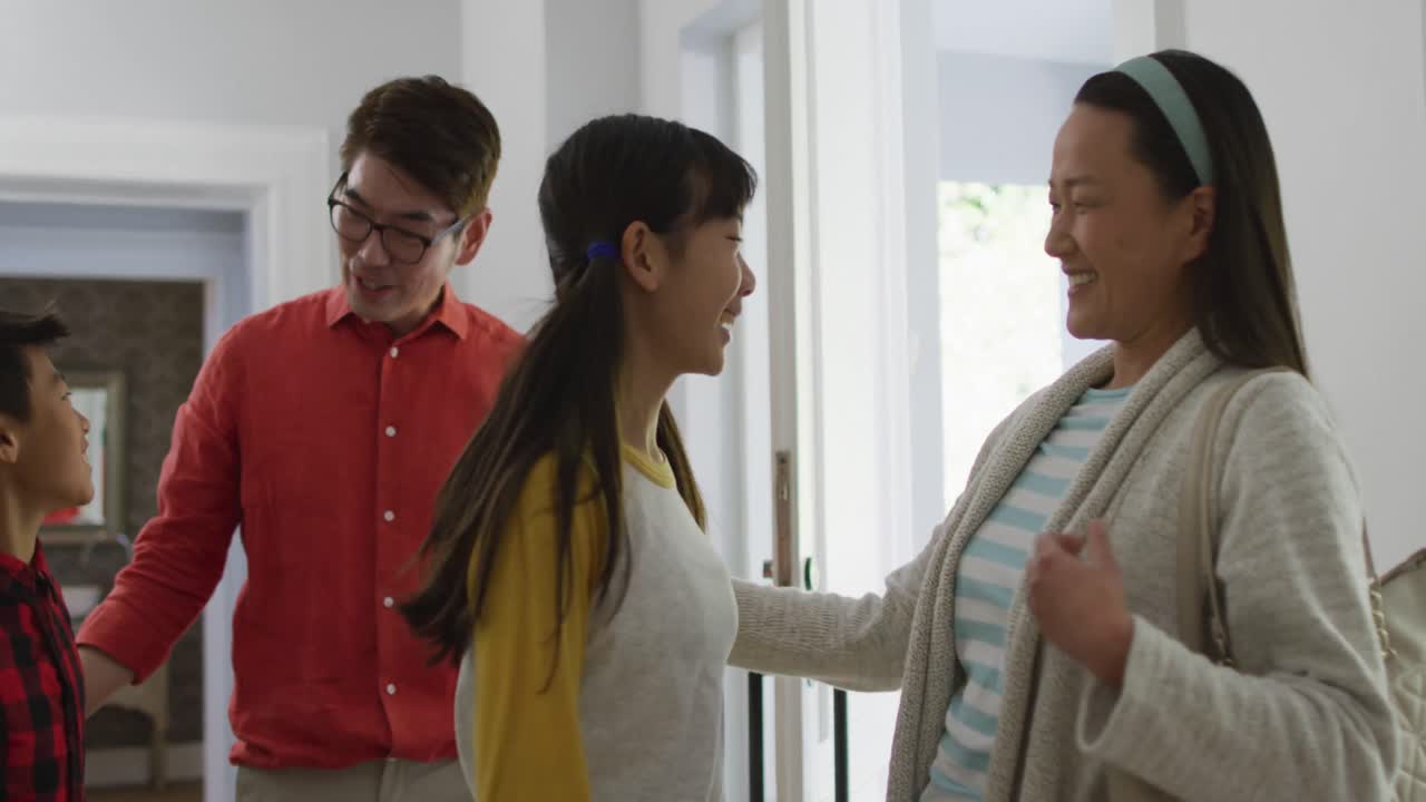 흥분 된 아시아인 아들 과 딸 이 집 으로 돌아오는 부모 를 포옹 하고 있다