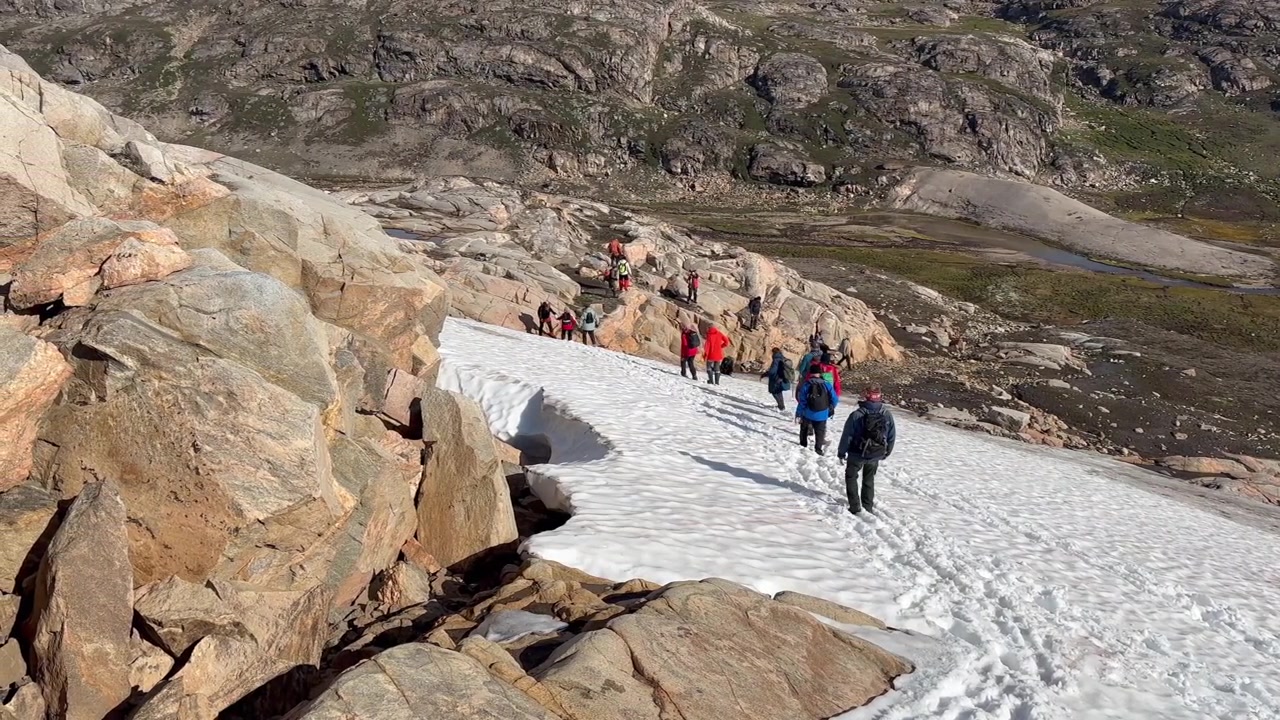Escursionisti scendono lungo un pendio innevato sull'isola di Danimarca, Scoresbysund, Groenlandia