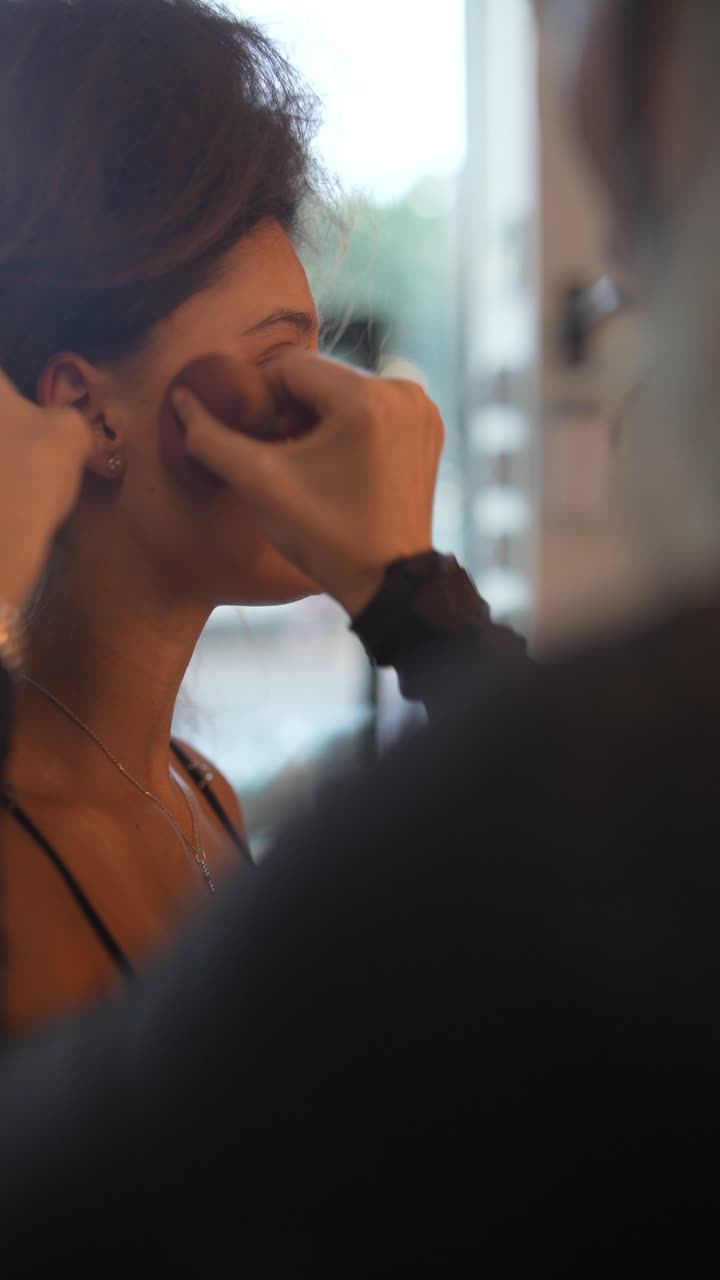 Professional Makeup Artist Applying Foundation to a Young Woman