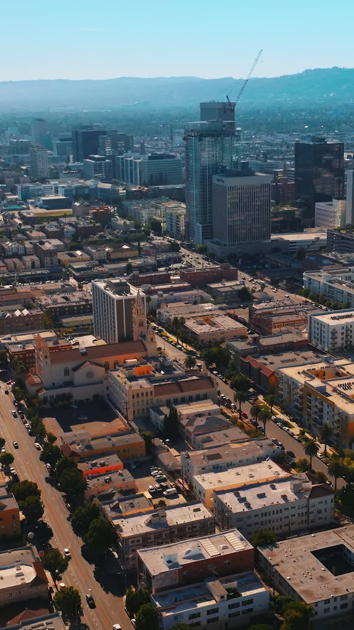 Los Angeles architecture on beautiful sunny daytime. Hazy mountains at backdrop of blue skies. Top view. Vertical video