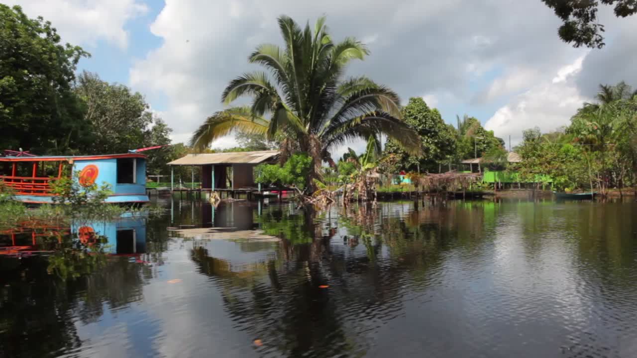 un barco navegando por el río negro entrando en un pequeño pueblo cerca del río amazonas en manaos, brasil.